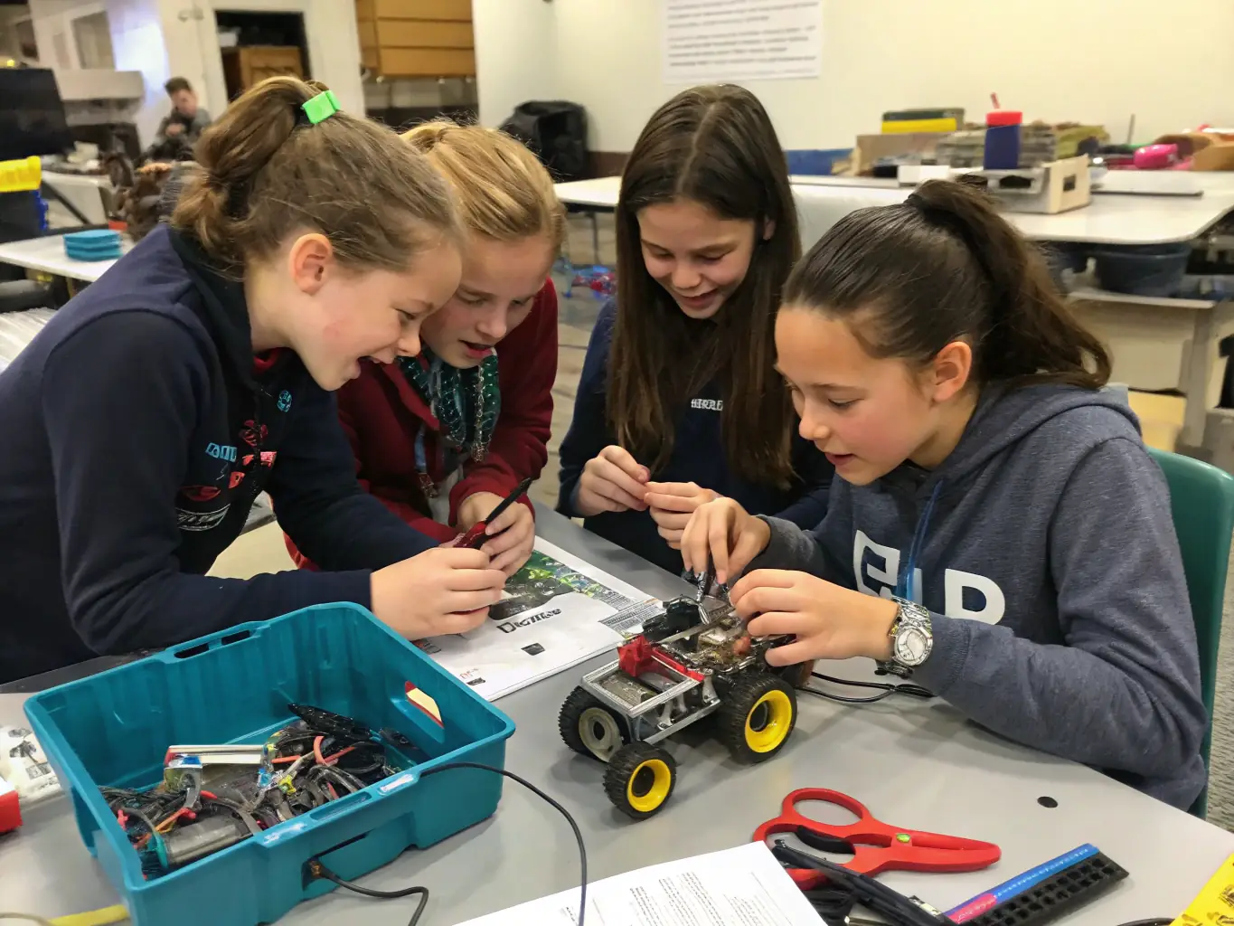 A group of young women working on a robotics project, assembling and programming robots with guidance from mentors.